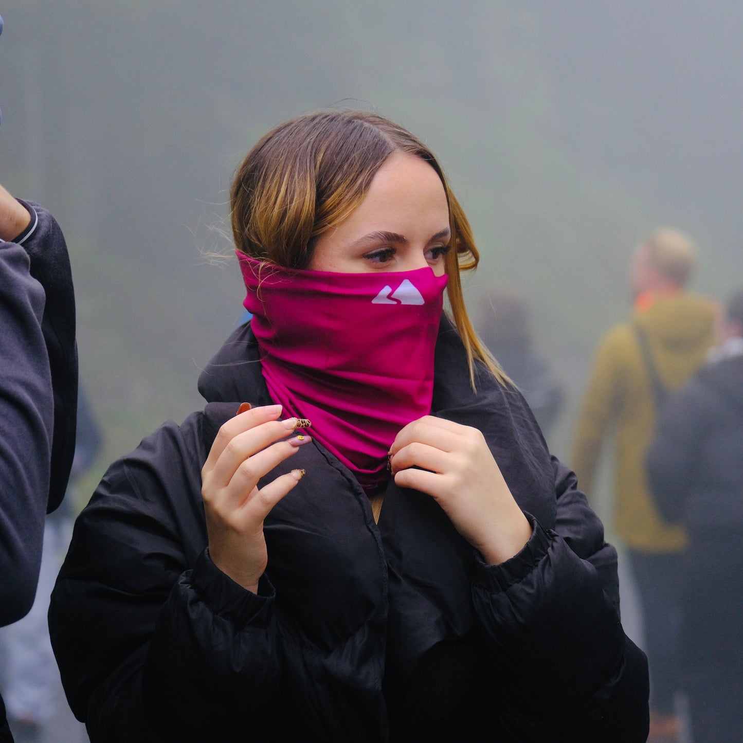 Neck gaiter displayed in a female model. With a white mountain logo. Burgundy colour. 