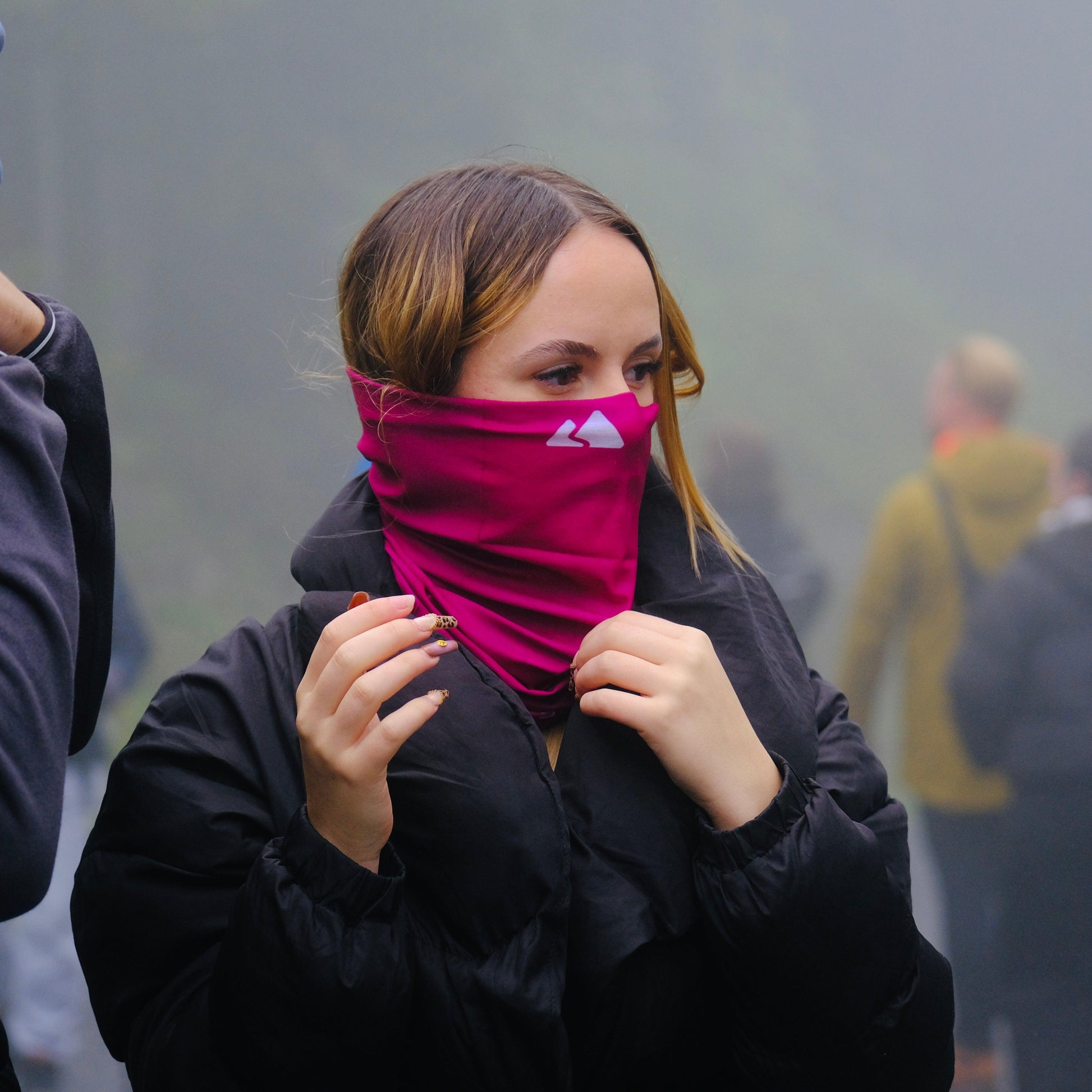 Neck gaiter displayed in a female model. With a white mountain logo. Burgundy colour. 